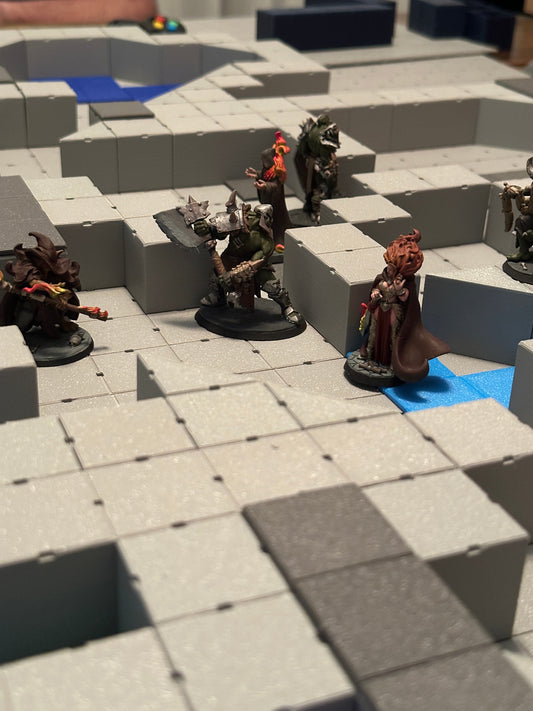 Creative tabletop setup with modular square terrain tiles being arranged for a custom map